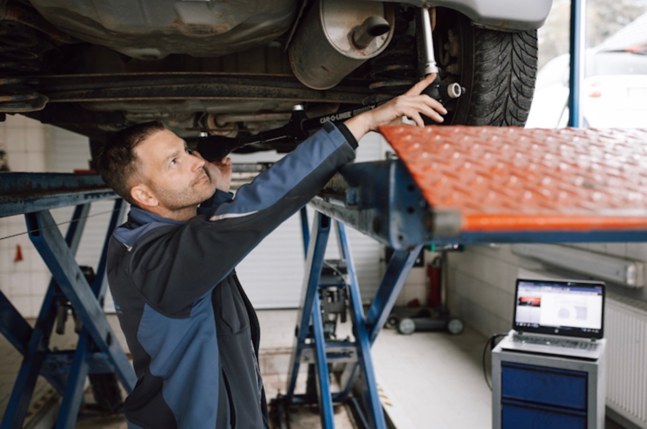 Jens Streubel prüft das Fahrwerk unter einem Fahrzeug auf der Hebebühne